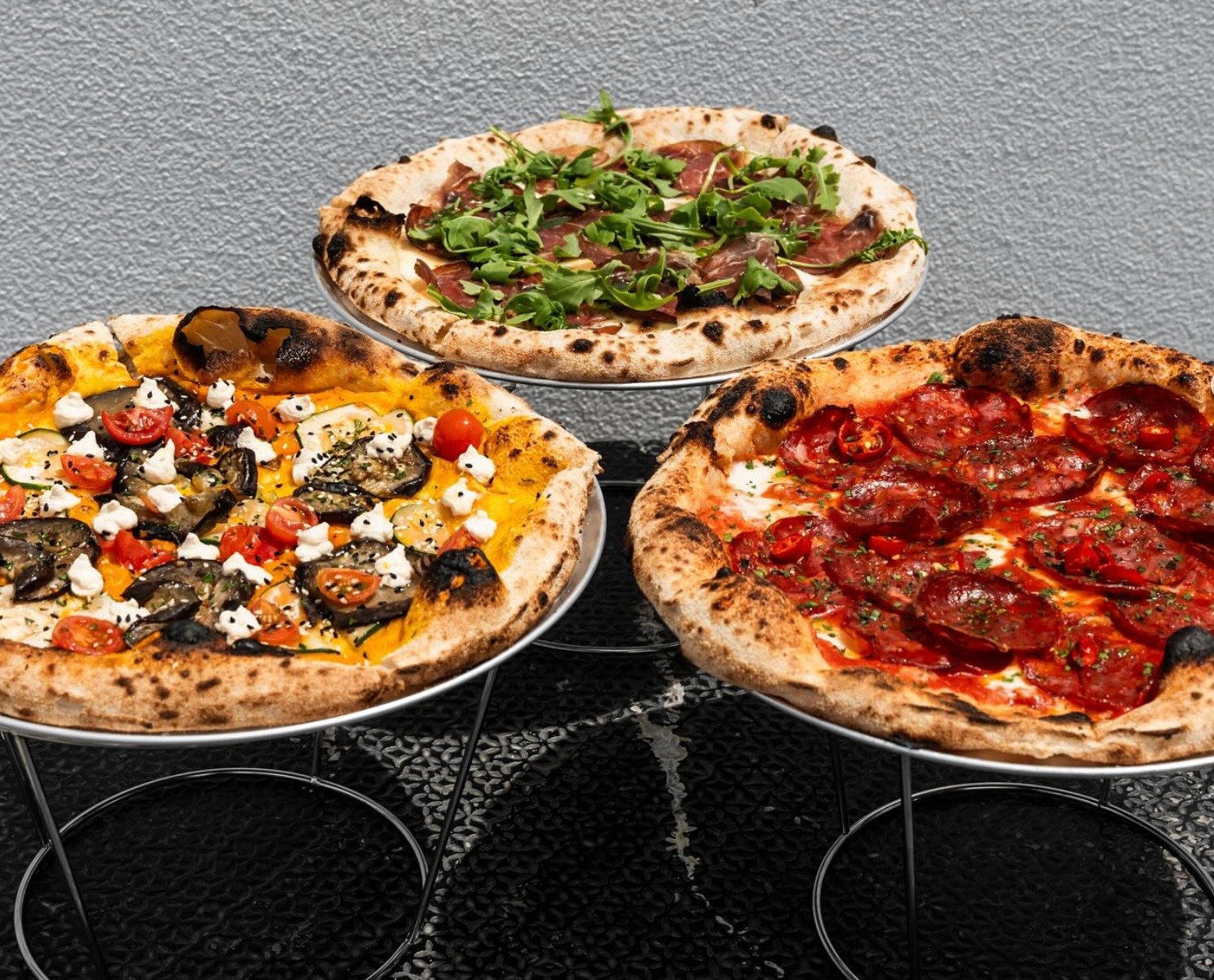 Three pizzas on wire stands
